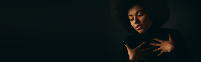 Beautiful young woman expresses emotion in stylish outfit against dark background