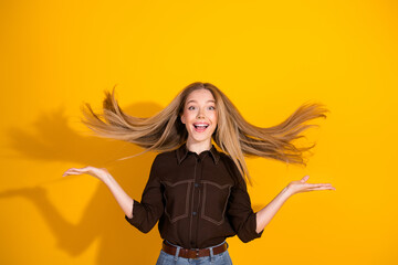 Young woman with blond hair smiling in casual fashion against a bright yellow background