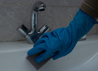 Woman cleaning bathroom sink with sponge