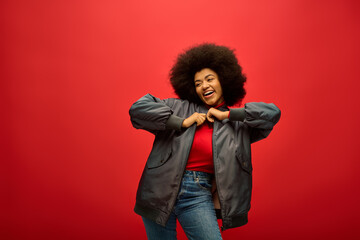 Stylish young woman joyfully dancing against a vibrant red backdrop