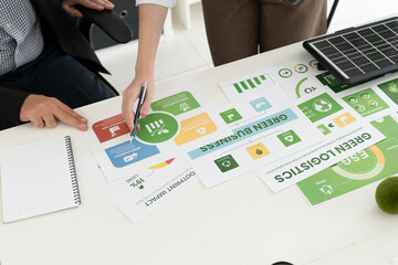 A diverse business team analyzing environmental charts and graphs in a collaborative meeting to create sustainable strategies in a modern office.