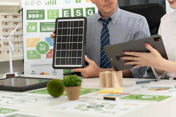 A diverse business team analyzing environmental charts and graphs in a collaborative meeting to create sustainable strategies in a modern office.