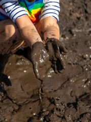 Child playing in mud. Selective focus.