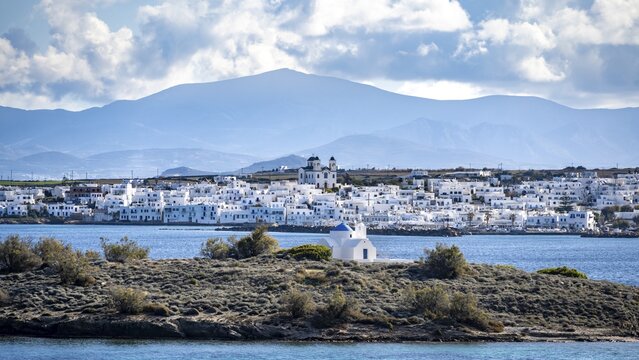Small island with church Agia Kali, village view of Naoussa town and blue sea, white Cycladic houses and church Agios Faneromeni, Paros, Cyclades, Greece