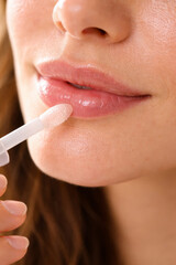 Naklejka premium Close-up of woman applying lip gloss with a wand