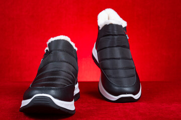 pair of black insulated sneakers for boy or man on red