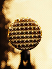 Close up of a golden vintage microphone on a golden studio background, music creation, singer songwriter concept