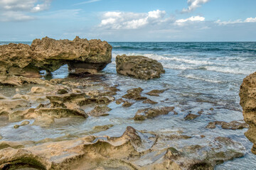 Fototapeta premium A rocky beach with a large body of water in the background. The rocks are scattered throughout the beach, and the water is calm. The scene is peaceful and serene