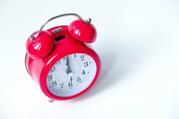 The classic red alarm clock is isolated on a white background
