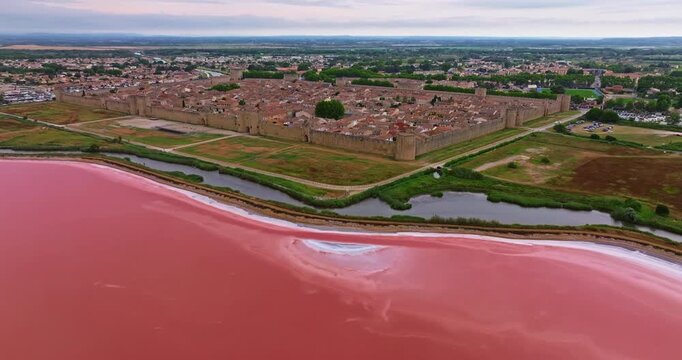 Aerial view of the medieval walled town of Aigues-Mortes near the pink salt lake on a sunny day, in the Camargue region, southern France