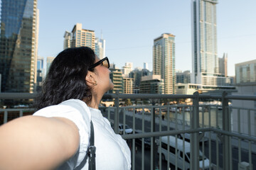 young woman making a vlog in Dubai Marina with modern architecture, Dubai traffic and luxury...