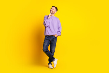 Young man in purple sweater posing thoughtfully against bright yellow background
