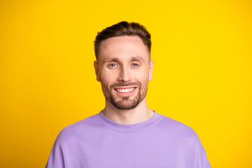 Fototapeta premium Young man smiling in purple hoodie against a bright yellow background for fashion lifestyle advertising