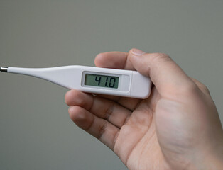 A hand holds a white digital thermometer displaying the high temperature reading of 41.0.