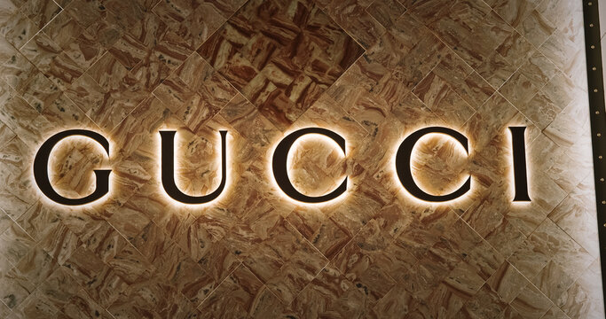 Shanghai, China. Gold Gucci Brand Backlit Logo On Shop Marble Wall. Gucci Brand Logo Of Italian Luxury Fashion House. House Of Gucci Is One Of Most Influential And Profitable Fashion Houses In World