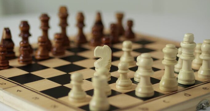 Adult hand makes chess move on board indoors. Chess action represents strategy and concentration. Chess decision highlights logic thinking. Game scene leadership and problem solving concepts.