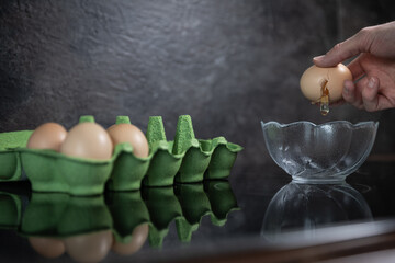 Side View of Modern Kitchen With Open Egg Carton and Cracking Egg
