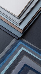 Stacked sheets of textured paper in various shades of blue and gray.