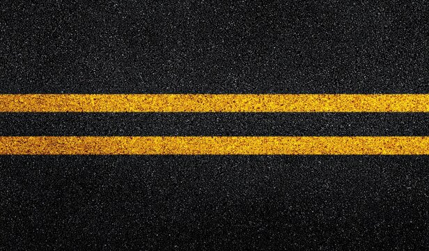 Close-up view of asphalt road with two bright yellow lane markings