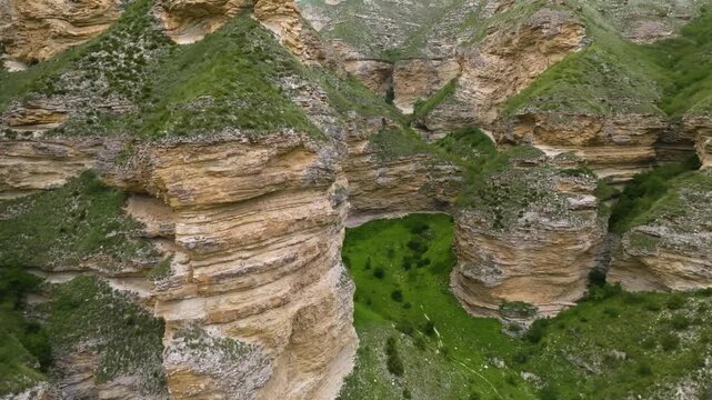 An aerial drone shot captures the stunning natural landscape of the Chongkatau Range in Dagestan, Russia, part of the Caucasus Mountains. The footage showcases massive, layered rock formations and cli