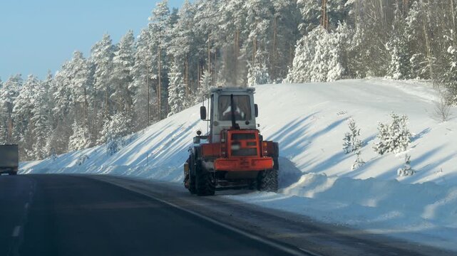 Snow removal scene. Snow plow operator clearing icy highway road. Bright winter day with snow cutting across intercity road. Snow removal on countryside road under clear sky with safety features