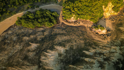 Aerial view of the rugged coastline, where lush green vegetation meets the textured sands of Pantai Kuta Lombok, creating a striking contrast, Kuta, Nusa Tenggara Barat, Indonesia.