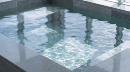 Rippling water in a modern indoor spa hot tub. Concept of relaxation, wellness and hydrotherapy with sunlight reflections