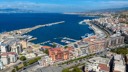 Fototapeta premium Aerial view of the port of Reggio Calabria, in southern Italy. It is a small marina overlooking the Strait of Messina. Sicily can be seen in silhouette on the horizon. It is a sunny summer morning.