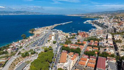 Fototapeta premium Aerial view of the port of Reggio Calabria, in southern Italy. It is a small marina overlooking the Strait of Messina. Sicily can be seen in silhouette on the horizon. It is a sunny summer morning.