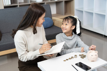 Obraz premium Financial Education. Mother teaching daughter about saving money with piggy bank.
