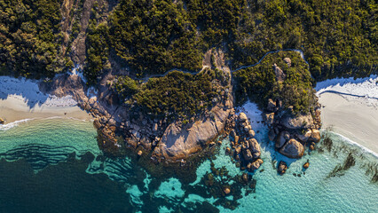 Aerial view of turquoise waters meeting pristine white sands and rocky outcrops fringed by lush greenery, Cape Le Grand, Western Australia, Australia.
