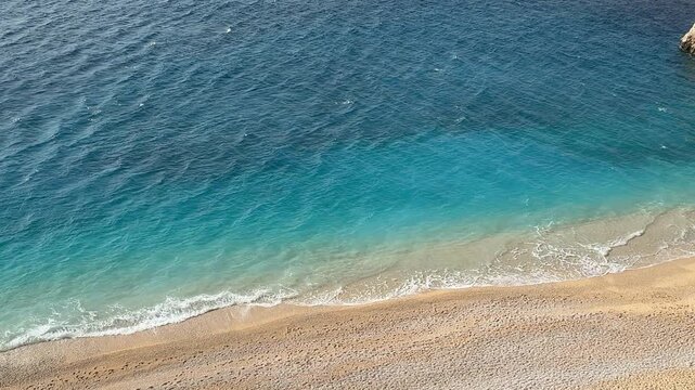 Aerial view of clear turquoise ocean waves on sandy beach with gentle gradient background