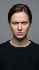 Obraz premium A captivating close-up portrait of a young woman displaying intense anger and profound frustration, her brow deeply furrowed, conveying powerful, raw emotion and dissatisfaction