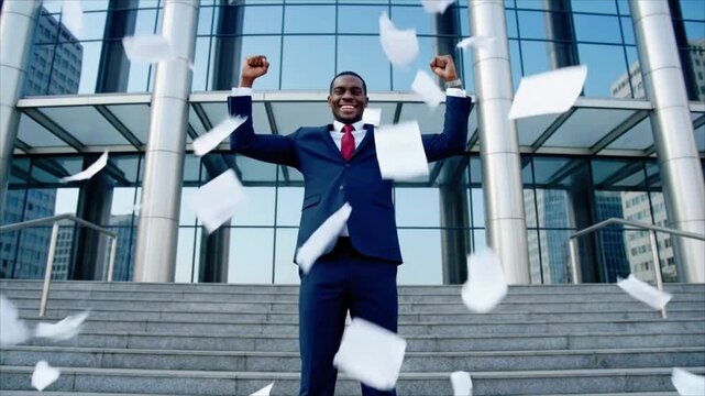 Happy businessman celebrates success throwing papers into air in slow motion, standing on stairs against office building
