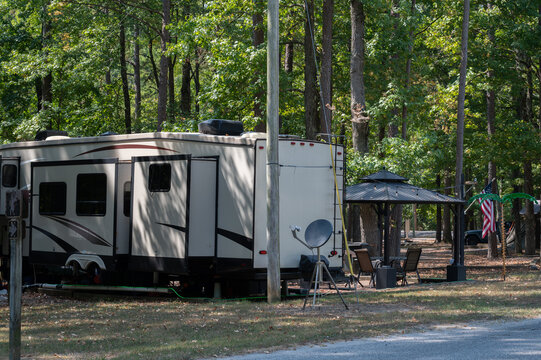 RV travel trailer parked in wooded campground site