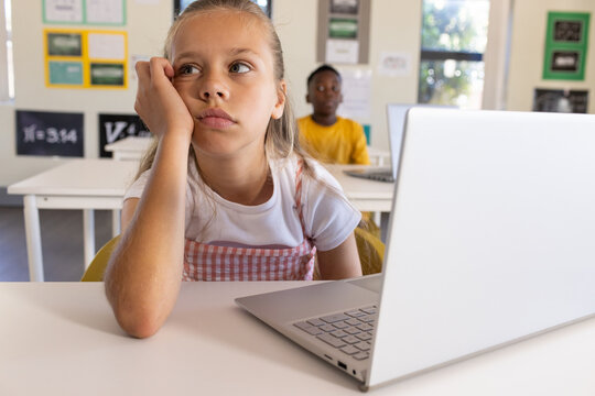 Classmates child girl in pink-dress resting at desk with laptop, African American boy in yellow tee