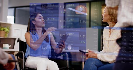 Leading woman in wheelchair in blue blouse holding tablet and gesturing during office stock tickers