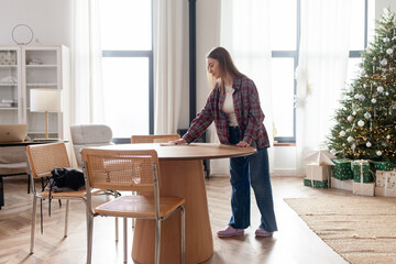 young woman cleans her home and dusts the table for Christmas, housewife tidies up and wipes down furniture