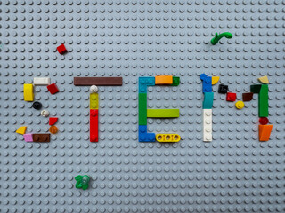 Naklejka premium STEM word built with multi-colored LEGO toy bricks on a gray baseplate, Direct top view, symbolic of early childhood engineering and science education: 25.05.2024- Ljubljana, Slovenia