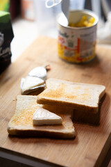 Freshly Toasted White Bread Slices with Cheese Wedges on a Wooden Cutting Board