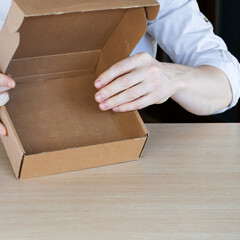 Person inspecting empty cardboard box on table