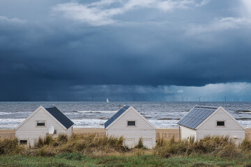 Obraz premium Beach huts on the beach of Katwijk aan Zee in the Netherlands on the North Sea coast under a cloudy sky.