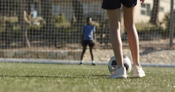 Youth kicker adjusting ball, running, kicking shot on goal for drill as keeper lunging, copy space