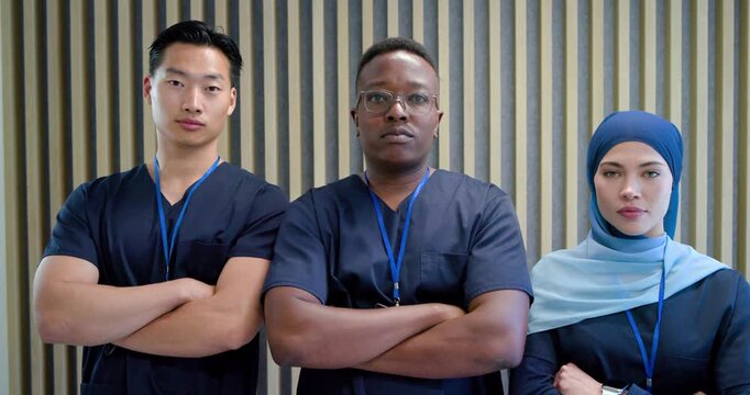 Diverse medical team standing crossing arms smiling for portrait at clinic navy scrubs blue IDs