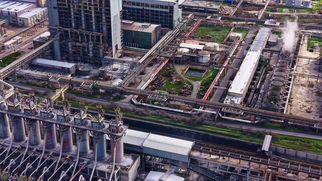 A large industrial area shows multiple buildings, pipes, and storage tanks. The setting indicates active operations with equipment positioned throughout the scene.