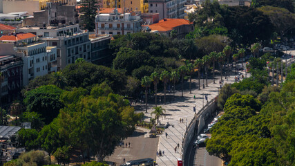 High-angle aerial view of a wide pedestrian promenade lined with palm trees and dense green foliage. It is located in the historic center of Reggio Calabria, southern Italy. © Stefano Tammaro