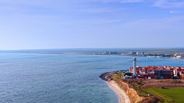 Flight near the shore of the Black Sea. View on the Aheloy lighthouse standing among the colorful residential houses. Bulgaria.