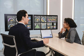 Business professionals analyzing data and discussing financial reports with digital dashboards and graphs in a modern office setting, focusing on strategy and performance.
