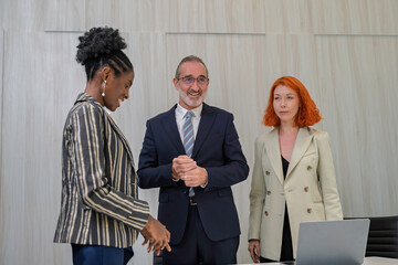 Business professionals shaking hands during a meeting in a modern office. Successful partnership, diverse teamwork, corporate collaboration, and career opportunity concept.