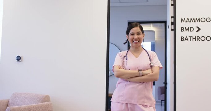 Woman nurse in scrubs, stethoscope at door, laughing, reacting to offcamera colleague, copy space